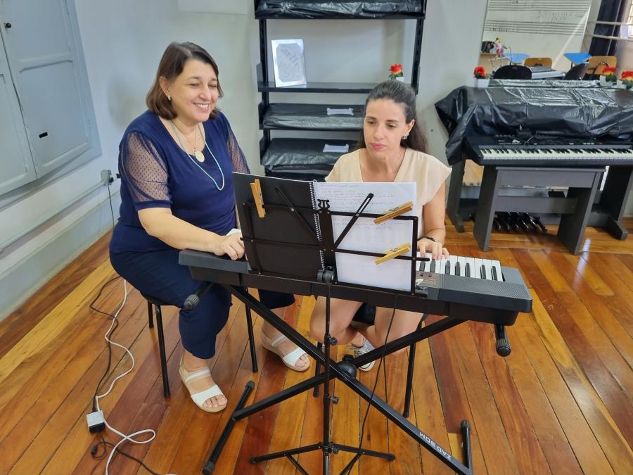 Professora ensinando seu aluno a tocar piano e gravar aula online