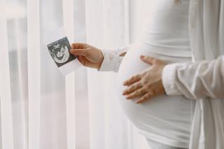 mulher-gravida-em-pe-perto-da-janela-olhando-para-uma-foto