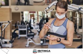 woman-with-medical-mask-at-the-gym-using-hand-sanitizer